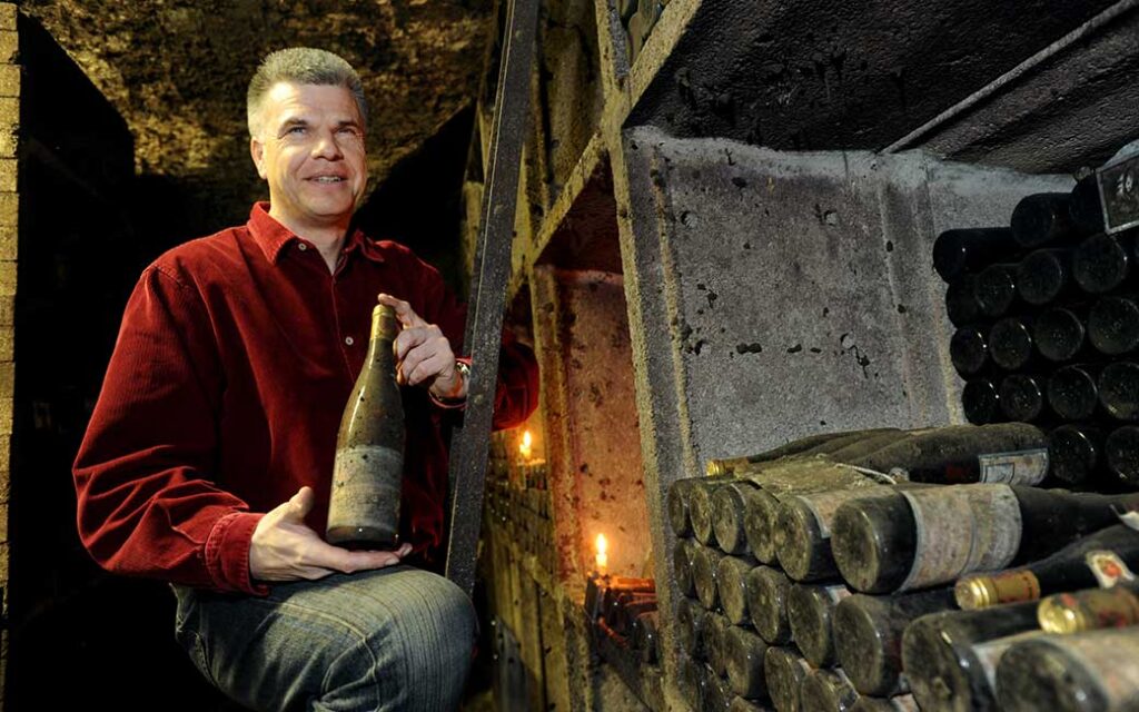 Geschäftsführer Ronald Müller-Hagen in der Schatzkammer mit einer Flasche gereiftem Rieslingwein in der Hand