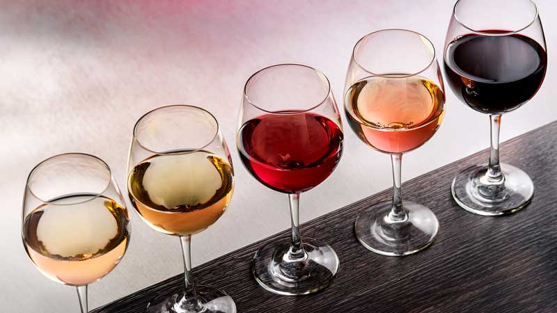 Gefüllte Weingläser in Reihe aufgestellt mit Weißwein, Rotwein und Roséwein