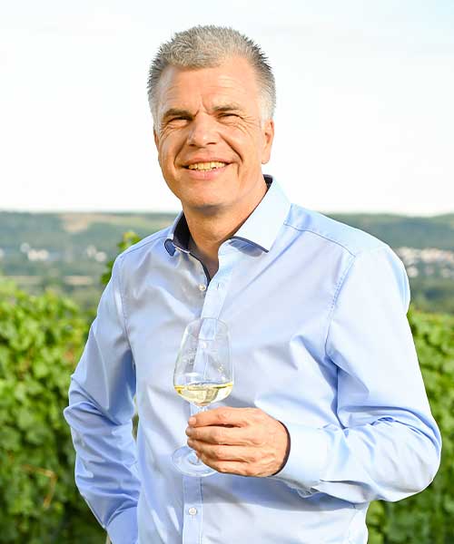 Geschäftsführer Ronald Müller-Hagen der Winzer von Erbach eG mit Weißweinglas in der Hand im Weinberg